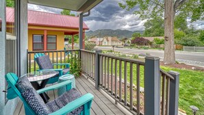 A covered porch with teal chairs and a glass table, overlooking a street with houses and a mountain range. - Nita's Place- Live like a local! Close to town! (Salida)