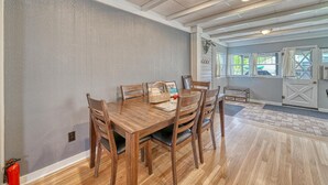 A dining area with a wooden table and chairs, a fire extinguisher, and a view of the outside through a door. - Nita's Place- Live like a local! Close to town! (Salida)
