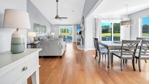 A spacious living area with a sofa, dining table, and chairs, a ceiling fan, and a view of the outdoors. - Bay View, Six-Seat Golf Cart, Pet Friendly, Linkside Village 434 (Miramar Beach)