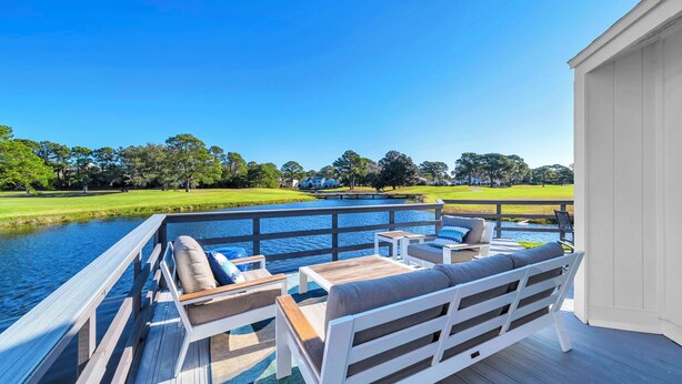 A deck with outdoor furniture overlooking a body of water and a golf course. - Bay View, Six-Seat Golf Cart, Pet Friendly, Linkside Village 434 (Miramar Beach)