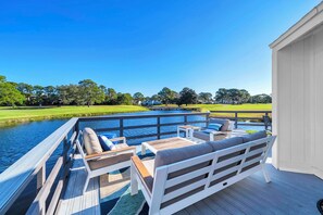 Terraza con mobiliario exterior con vista a un cuerpo de agua y un campo de golf.