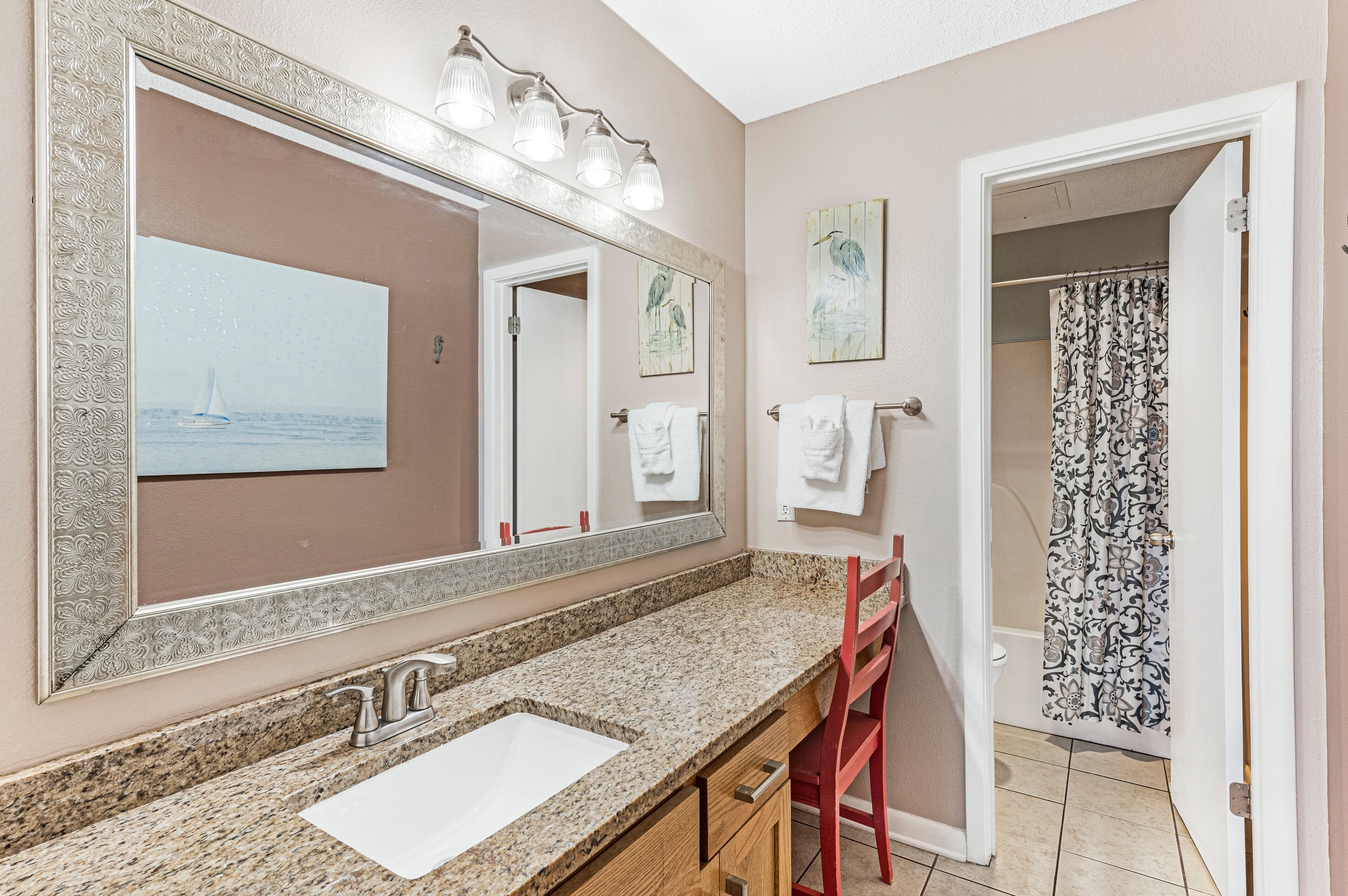A bathroom with a granite countertop, a large mirror, and a shower curtain with a paisley pattern.
