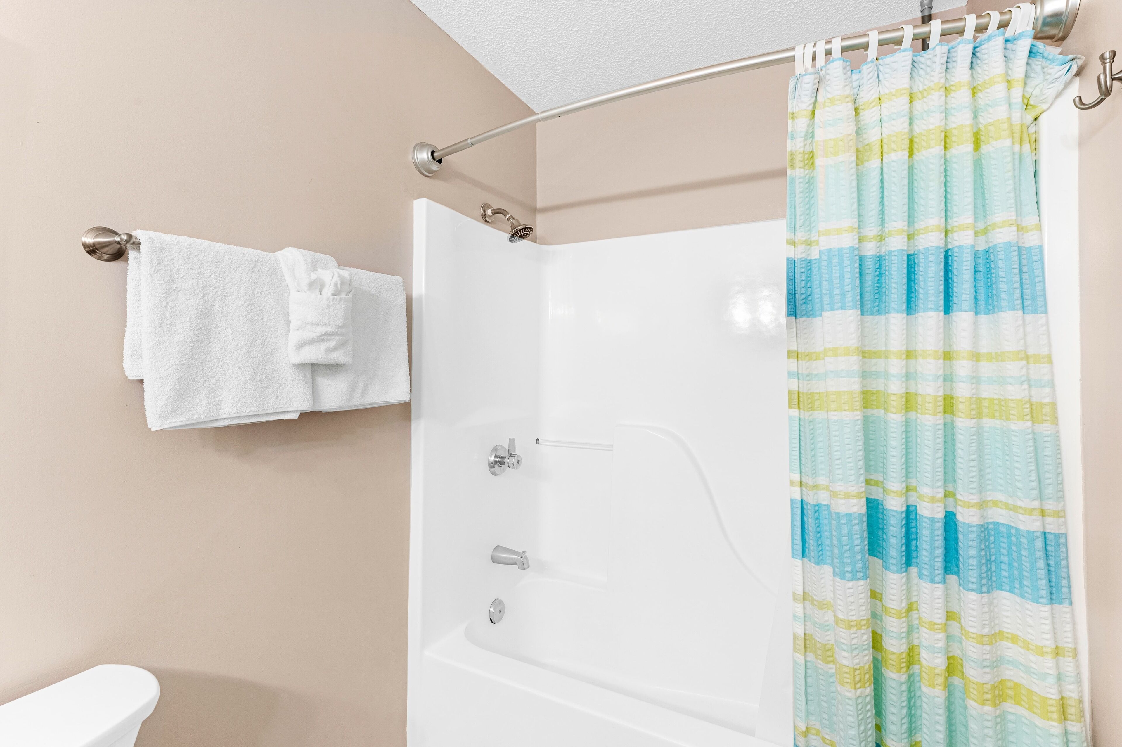 A bathroom with a white bathtub, a shower curtain, and a towel rack with two towels.