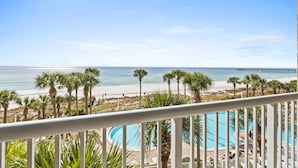 Un balcon avec vue sur une plage, des palmiers et une jetée.
