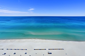 Une plage bordée de rangées de transats et offrant une vue dégagée sur l’océan.
