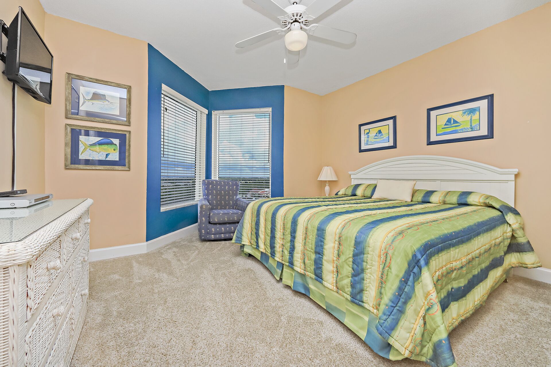 A bedroom with a bed, a chair, a desk, and a ceiling fan.