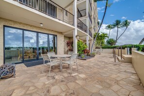 A multi-story building with a patio area featuring outdoor furniture and a view of the ocean.