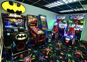 A room with arcade games including Batman, The Dark Knight, and Crash Course.