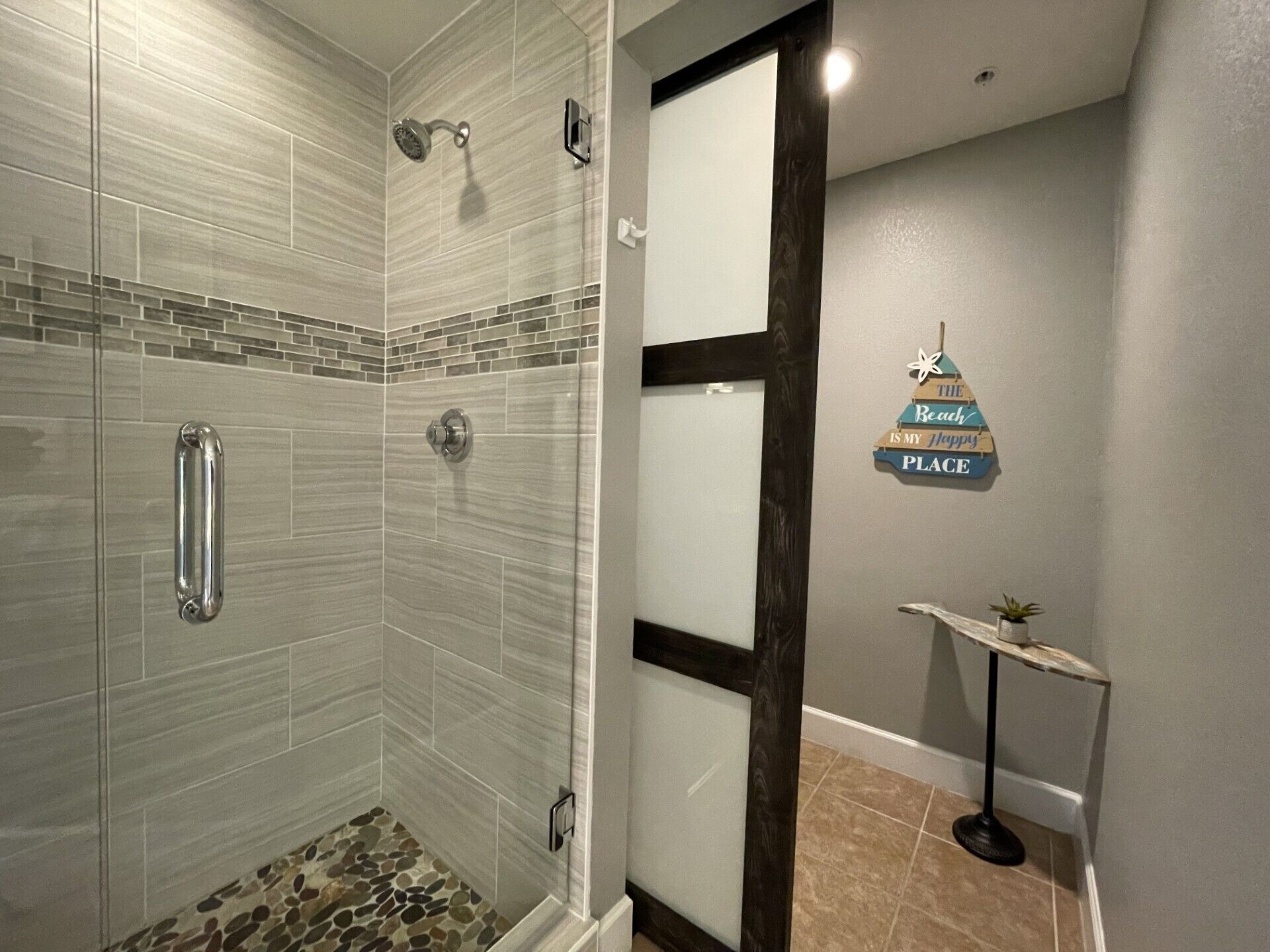 Ein modernes Badezimmer mit Dusche, gefliesten Wänden und einem dekorativen Schild an der Wand.