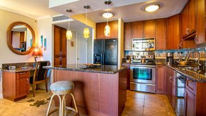 A modern kitchen with wooden cabinets, a central island, stainless steel appliances, and pendant lighting.
