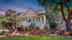 A two-story house with a balcony, surrounded by trees and a well-maintained lawn. - Hartnett Blvd 3502: 3  BR, 2  BA House in Isle of Palms, Sleeps 8 (Isle of Palms)