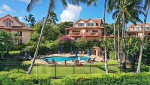 A resort with a swimming pool, palm trees, and multiple buildings with balconies. - Makanui 612 Gorgeous Mountain View By Suite Paradise (Koloa)