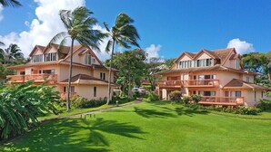 A resort with two-story buildings, a well-maintained lawn, and palm trees. - Makanui 612 Gorgeous Mountain View By Suite Paradise (Koloa)
