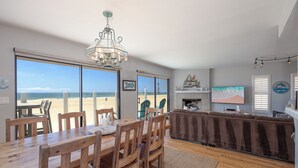 A dining area with a view of the beach, a chandelier, and a TV on the wall. - 1213O Local's Choice at Silverstrand (Oxnard)