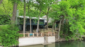 A lakeside property with a dock, wooden deck, and a covered outdoor area. - Riverside Roost- NB Guadalupe Riverfront + Easy River Access + Upper & Lower Decks + Minutes to Town (New Braunfels)