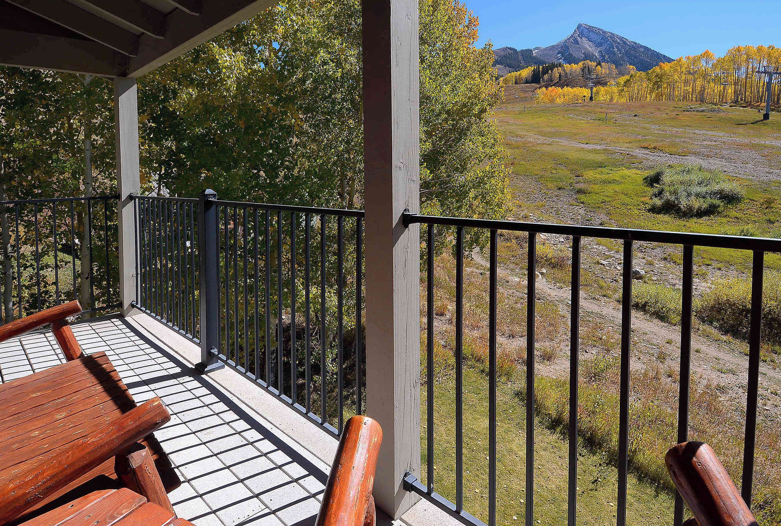 A balcony with a view of a mountainous landscape and autumn trees.