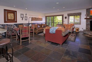 A spacious living area with a fireplace, a dining area with a table and chairs, and large windows providing a view of the outdoors. - Whetstone Vista- Beautiful 2 Br ski in/out,hot tub (Mt. Crested Butte)