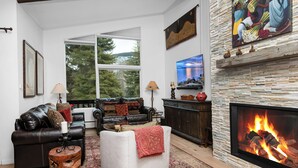 A living room with a fireplace, a sofa, a coffee table, and a fireplace mantle with decorative items. - Vail Village Condo, Walk to Golden Peak Lift/Ski School, Shops & Restaurants! (Vail)