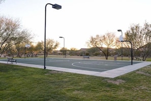 Un terrain de basketball en plein air, équipé de bancs et de lampadaires.