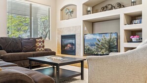 Ein Wohnzimmer mit Kamin, Fernseher und einer Couch.