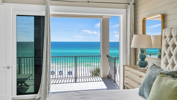 A bedroom with a balcony overlooking a beach, a bed with a lamp, and a dresser. - Not the Norm - Oceanfront Home with Private Pool & Beach Access (Miramar Beach)