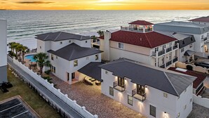 A multi-story hotel with a pool, balconies, and a view of the ocean at sunset. - Not the Norm - Oceanfront Home with Private Pool & Beach Access (Miramar Beach)