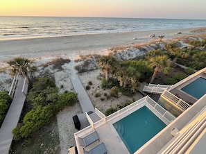 A beach view with a pool and outdoor seating.