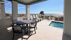 Un espacio al aire libre techado con piscina, sillas de descanso y vista a la playa.