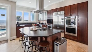 Una cocina moderna con una isla grande, electrodomésticos de acero inoxidable y vista al océano.