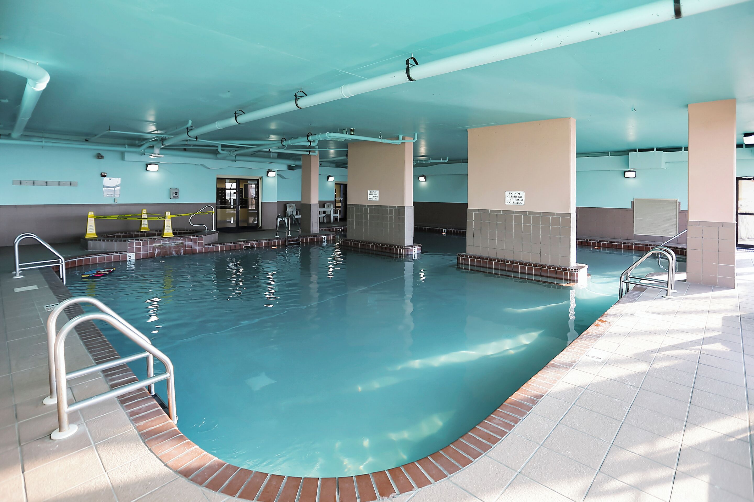 Ein Innenpool mit klarem Wasser, gefliesten Wänden und einem Fliesenboden.