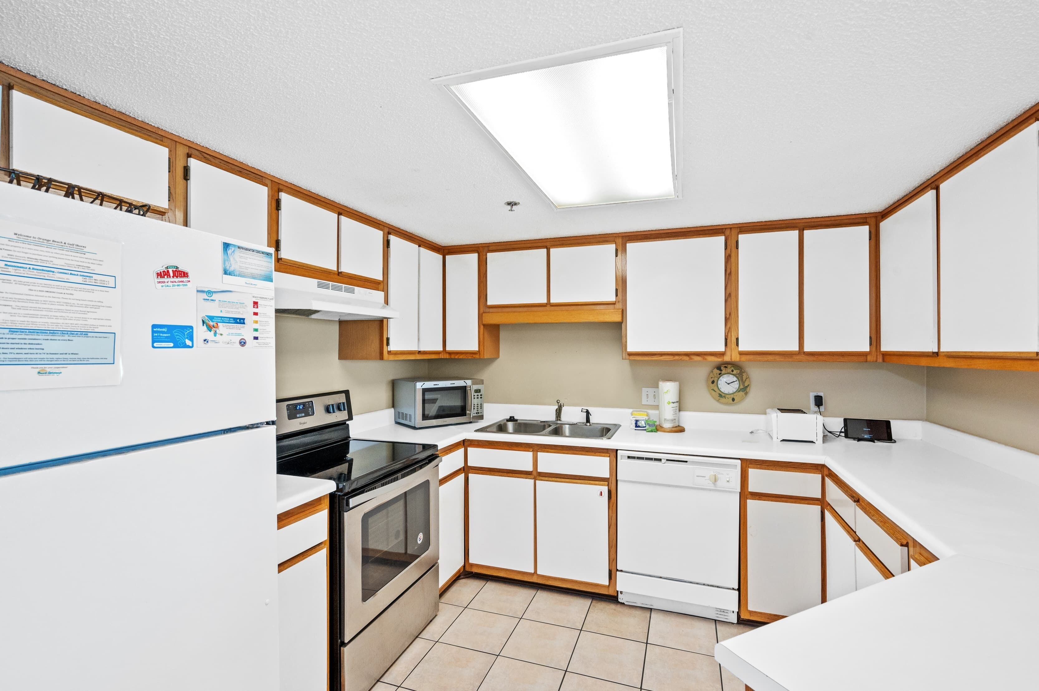 A compact kitchen with white cabinets, a microwave, a stove, and a refrigerator.