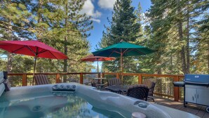 A hot tub with seating and umbrellas, surrounded by trees.