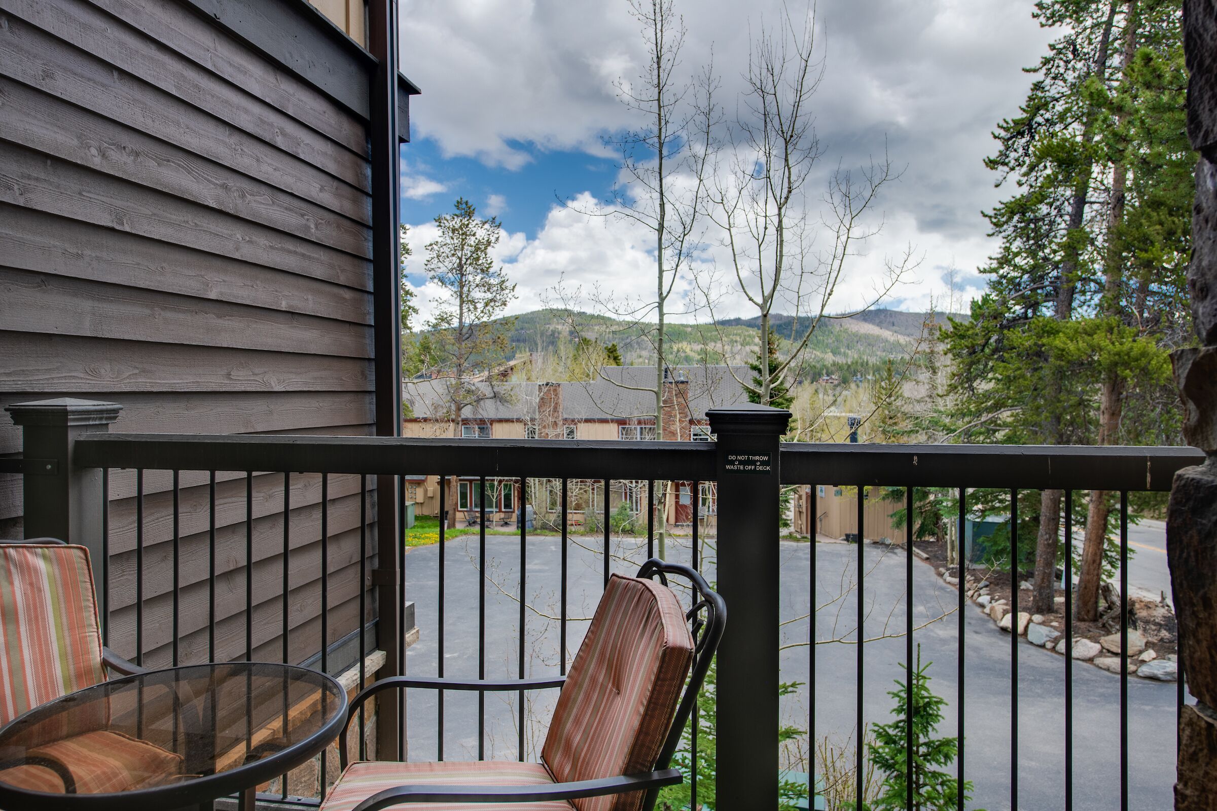 A balcony with a view of a parking area and distant hills.
