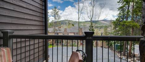 A balcony with a view of a parking area and distant hills.