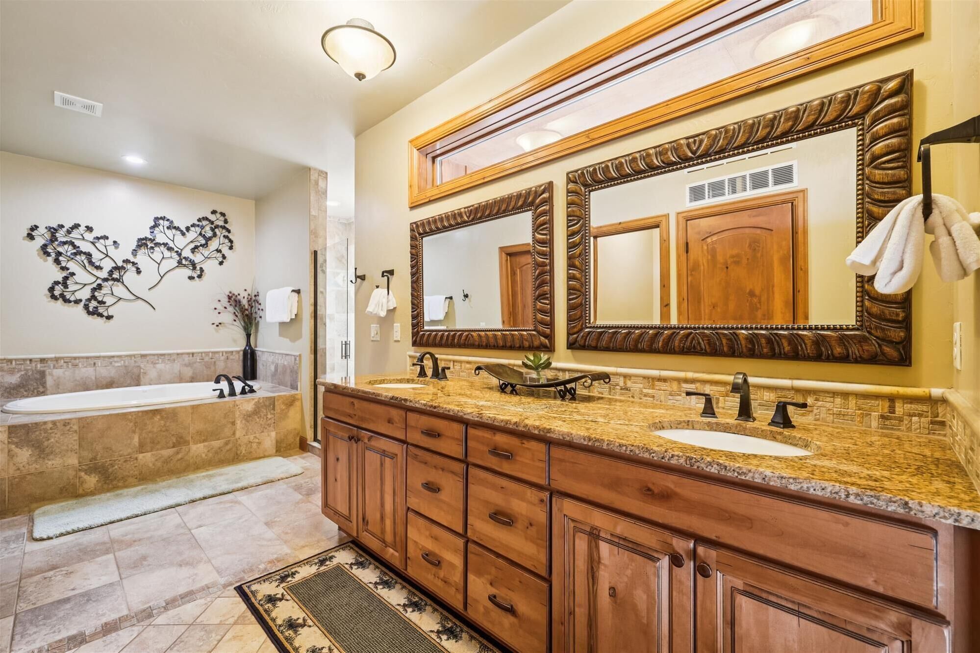 A bathroom with a double sink vanity, a large mirror, and a bathtub.
