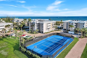 Un resort con varias edificaciones, una gran piscina azul y vista al océano.