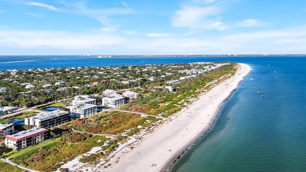 Luftaufnahme einer Küstenlandschaft mit Strand, Gebäuden und einer Brücke.