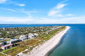 An aerial view of a coastal area with a beach, buildings, and a bridge. - BEACHCOMBER A101 - now open for Summer! (Sanibel)