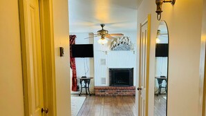 A hallway with wooden flooring, a fireplace, and a ceiling fan.