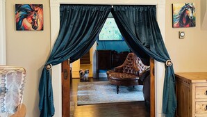 A room with a large window, a fireplace, and a dog sitting by the window.