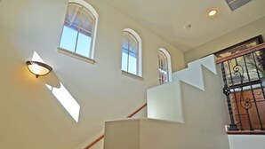 Een trap met een leuning, een lamp aan de muur en een raam met uitzicht op de lucht.