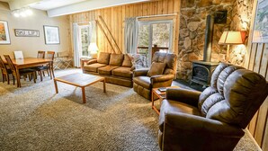 Ein gemütliches Wohnzimmer mit Steinwand, Kamin und Essbereich mit Tisch und Stühlen.