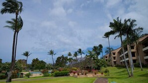 A resort with a pathway, palm trees, and a building with multiple balconies. - Kaanapali Royal L-101  Located on Golf Course (Lahaina)