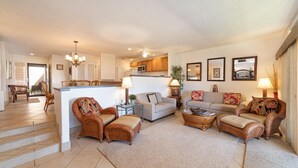 A spacious living area with a central island, wicker furniture, and a kitchen in the background. - Kaanapali Royal L-101  Located on Golf Course (Lahaina)