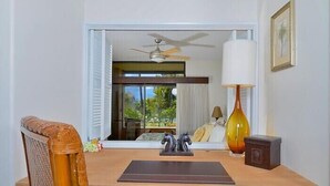 A room with a desk, a chair, a window with blinds, a ceiling fan, a lamp, and a vase. - Kaanapali Royal L-101  Located on Golf Course (Lahaina)