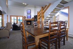 Un coin repas avec une table et des chaises en bois, une cheminée et une vue sur l’extérieur.