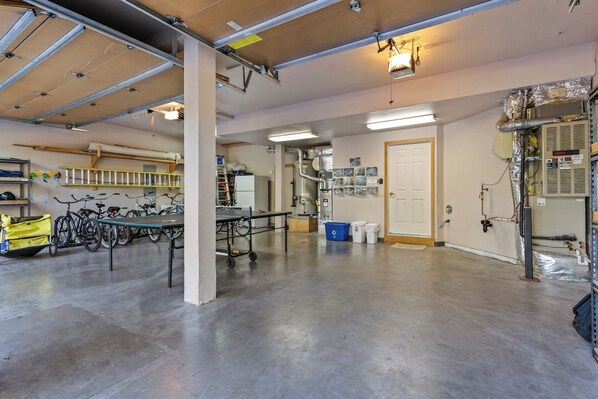 A spacious indoor area with a concrete floor, bicycles, a table, and various equipment. - 11 Tournament - Golf Course Executive, Pool Table, Hot Tub, Bikes, A/C, SHARC Passes, Fireplace (sunriver)