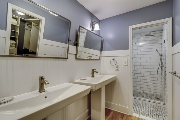 Un baño con dos lavamanos, un espejo y una ducha.