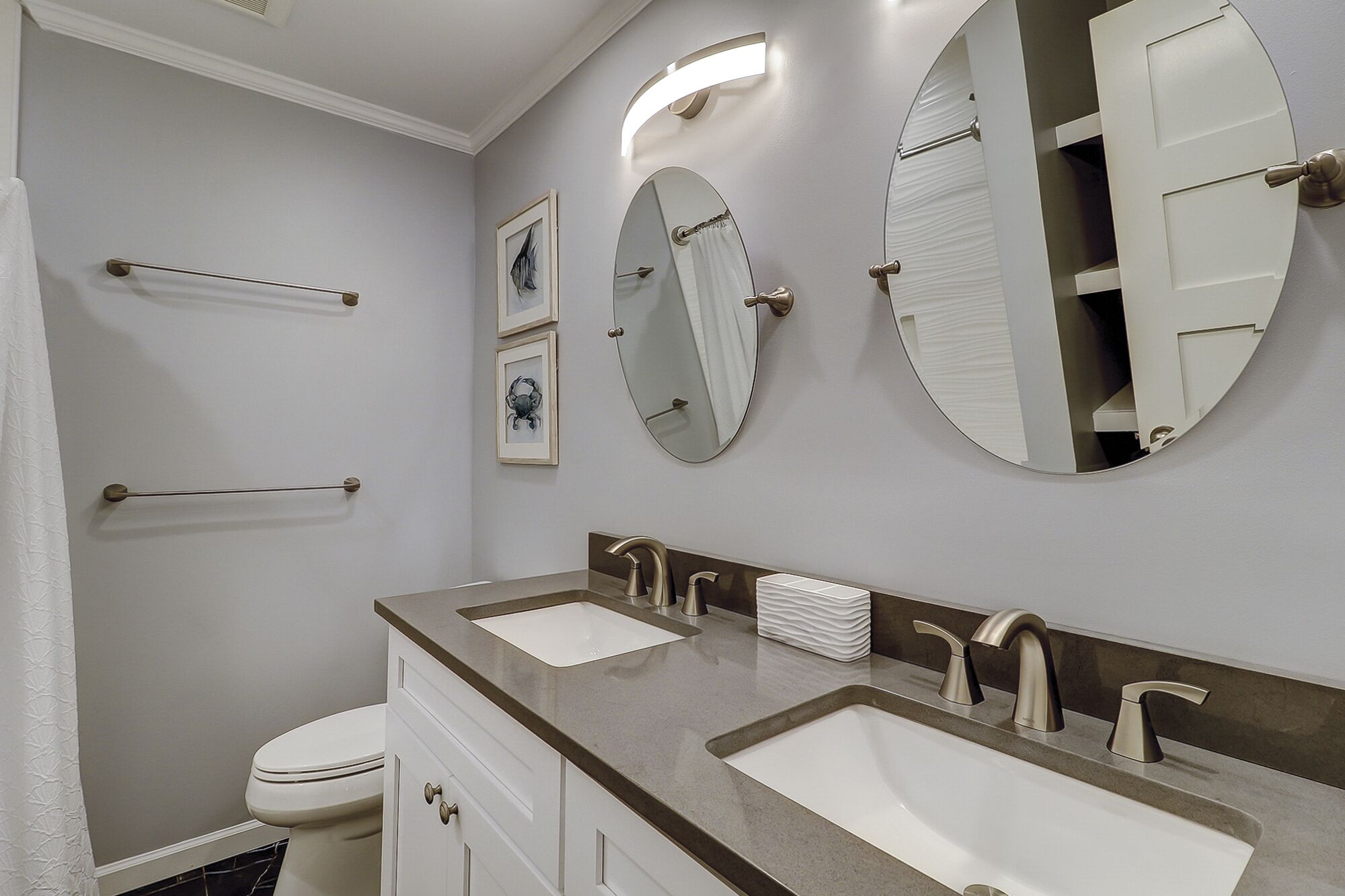 Une salle de bain avec deux lavabos, des toilettes et trois miroirs.