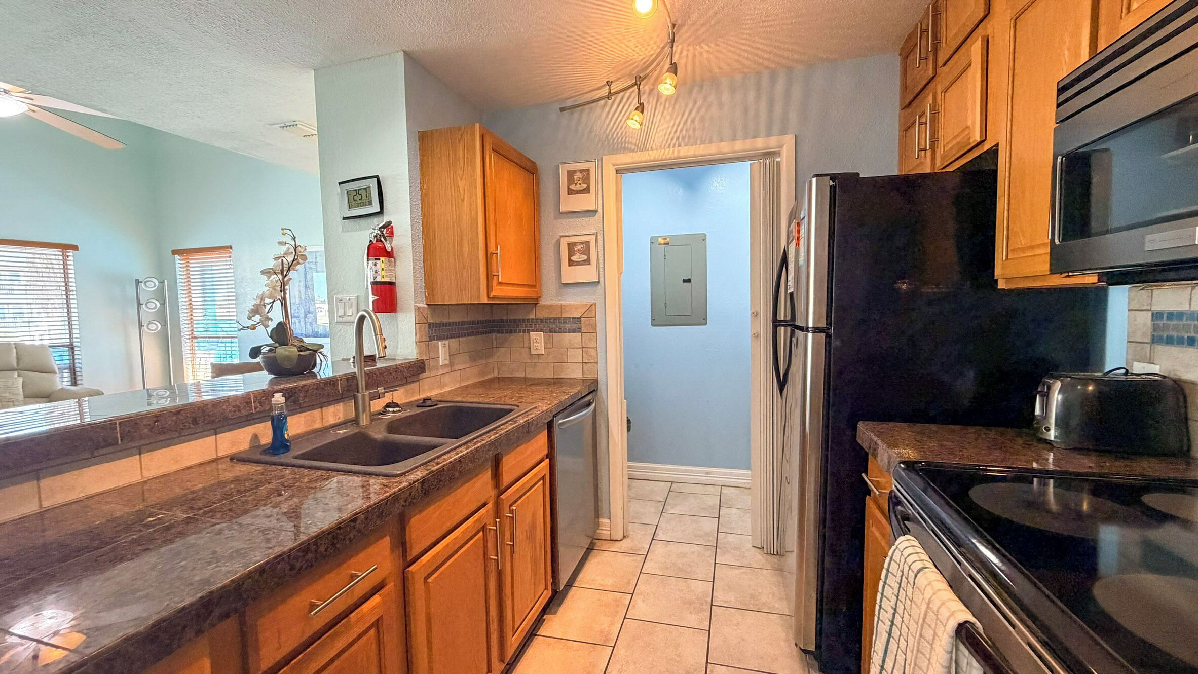 A kitchen with wooden cabinets, a stainless steel refrigerator, a microwave, and a dishwasher.